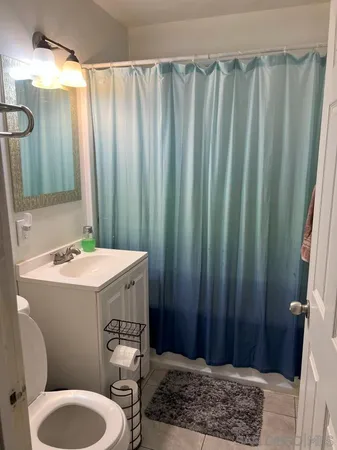 a bathroom with a sink a toilet a mirror and shower curtain