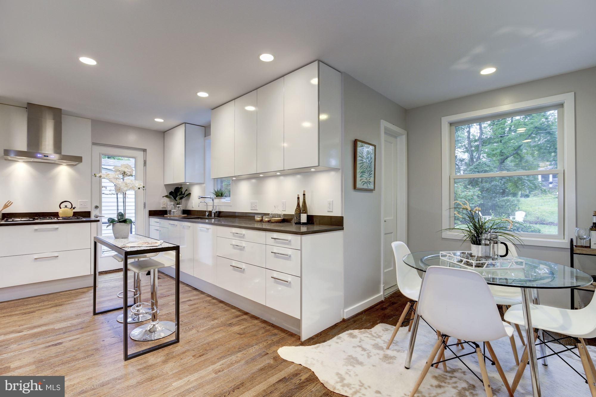 4814 Sedgwick Street Northwest Washington, DC 20016 - Photo 4 of 30 a kitchen with a dining table chairs and white cabinets