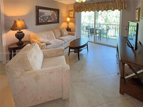 a living room with couches a flat tv screen and next to a window