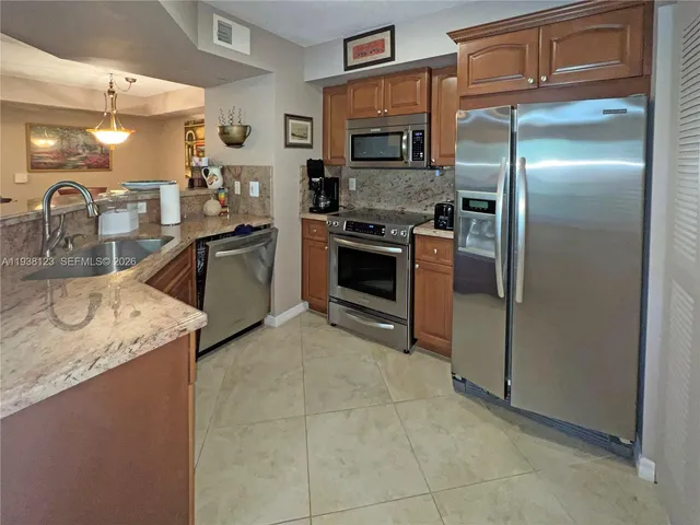 a kitchen with stainless steel appliances granite countertop a sink and a refrigerator