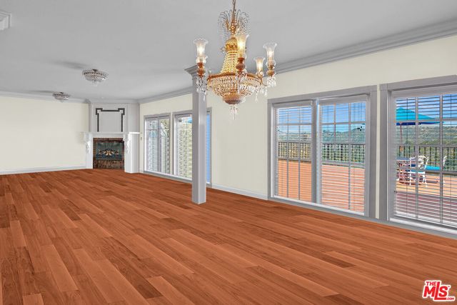 a view of an empty room with wooden floor and a fireplace