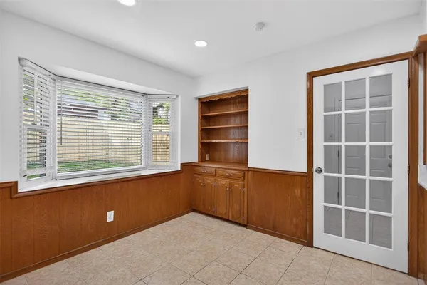 a view of an empty room with a window and wooden cabinets