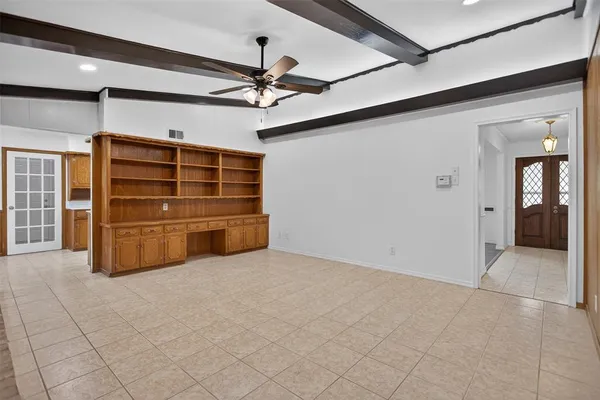 a view of an empty room with cabinet and a ceiling fan