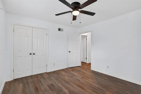 an empty room with wooden floor a ceiling fan and staircase