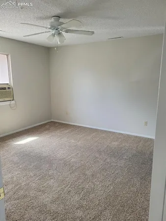 an empty room with a ceiling fan and window