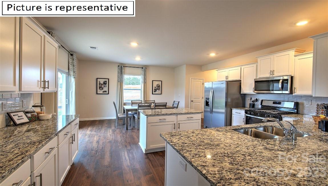 111 Beech Tree Lane Locust, NC 28097 - Photo 15 of 37 a kitchen with stainless steel appliances granite countertop a stove top oven a sink dishwasher a refrigerator and white cabinets with wooden floor