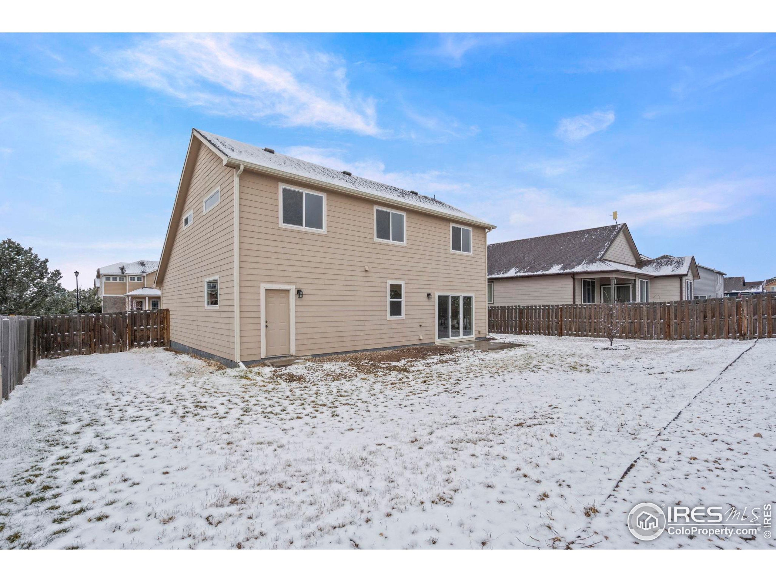 7324 Atlantis Street Wellington, CO 80549 - Photo 26 of 31 a view of a grey house with a wooden fence