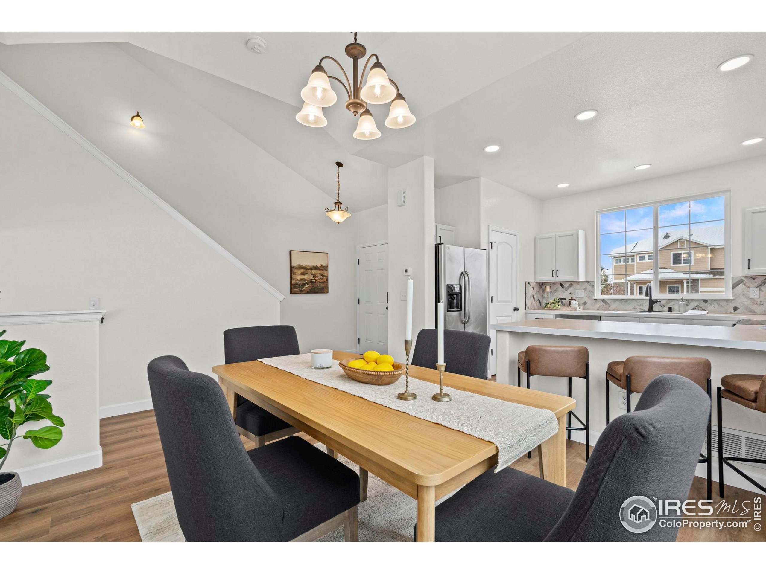 7324 Atlantis Street Wellington, CO 80549 - Photo 4 of 31 a dining room with kitchen island a dining table wooden floor stainless steel appliances and kitchen view
