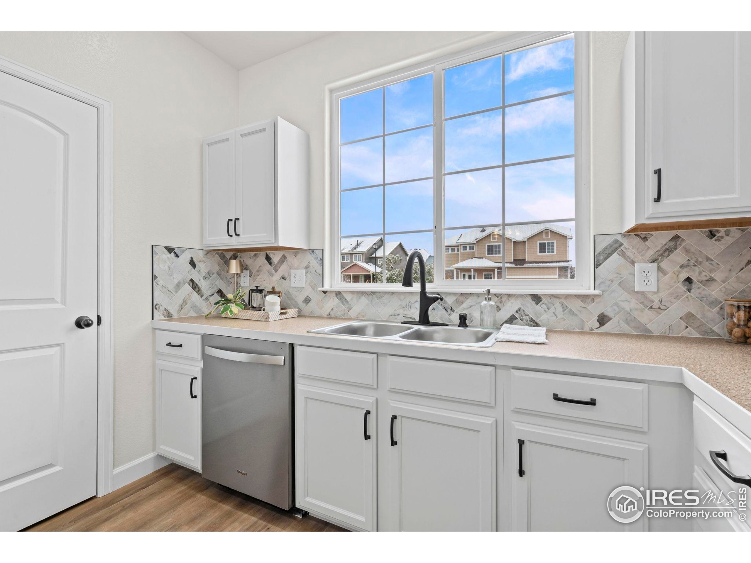 7324 Atlantis Street Wellington, CO 80549 - Photo 8 of 31 a view of cabinets a sink and a window in a white kitchen