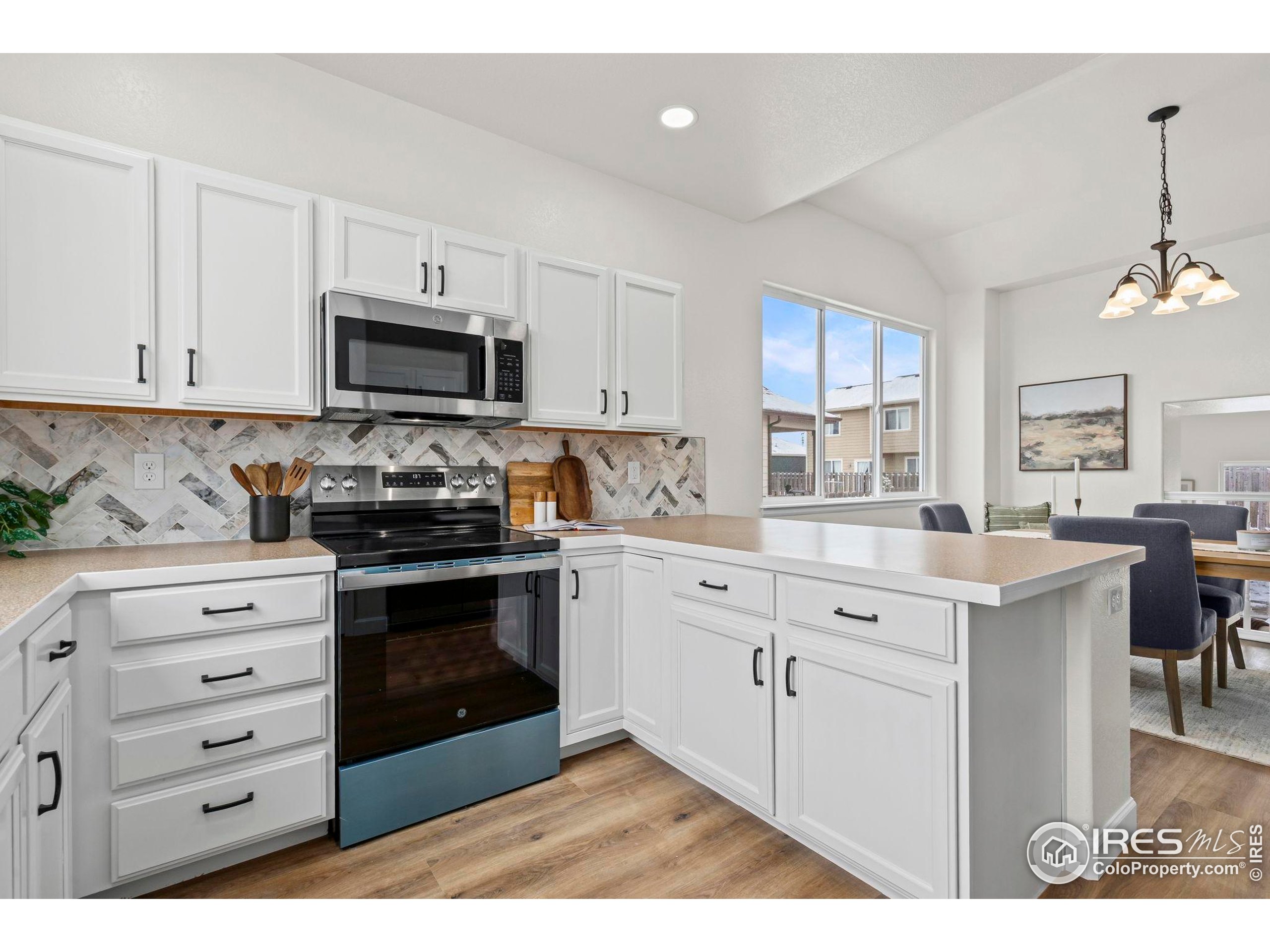 7324 Atlantis Street Wellington, CO 80549 - Photo 9 of 31 a kitchen with granite countertop white cabinets and stainless steel appliances