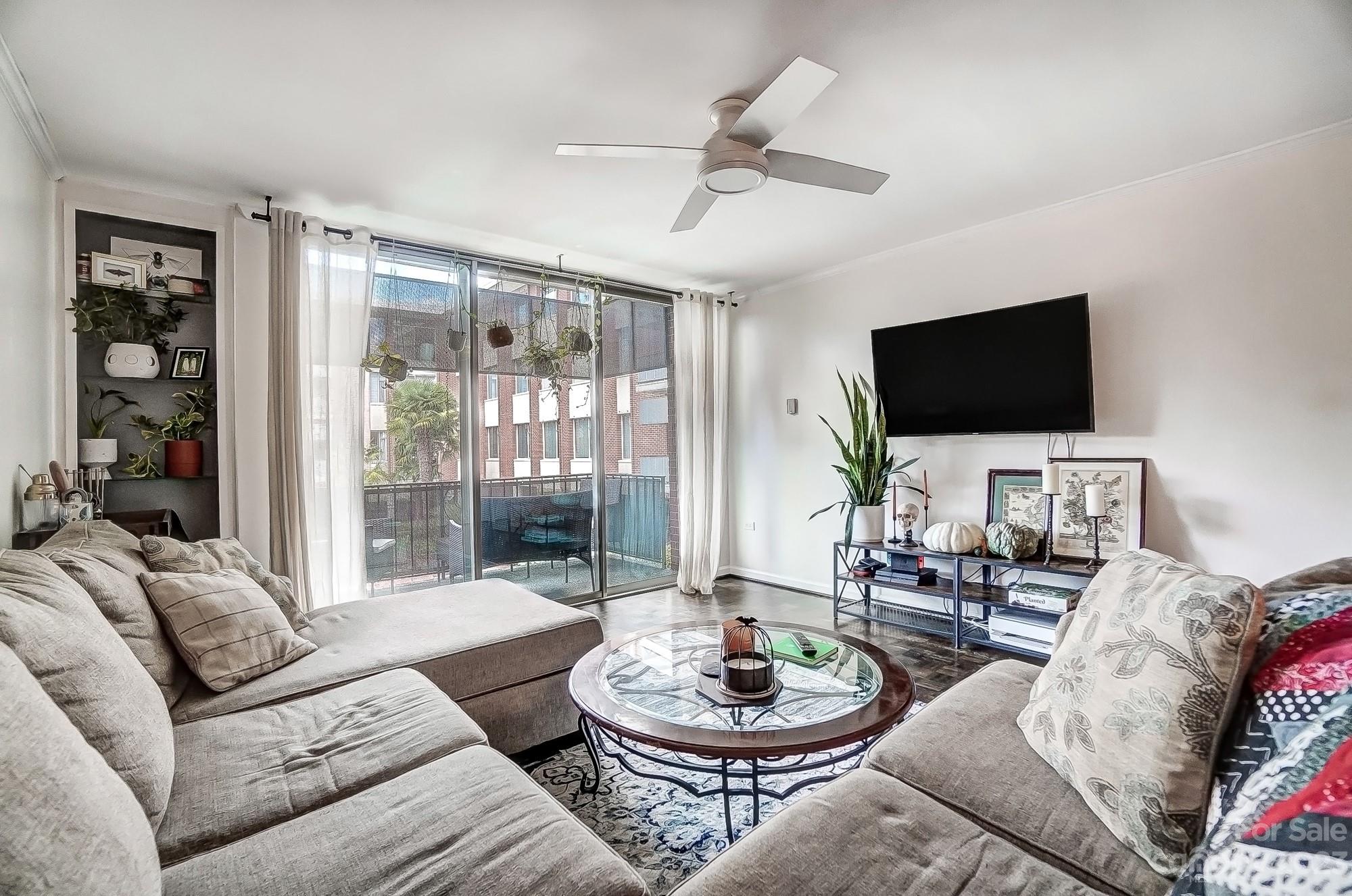 a living room with furniture a flat screen tv and a large window