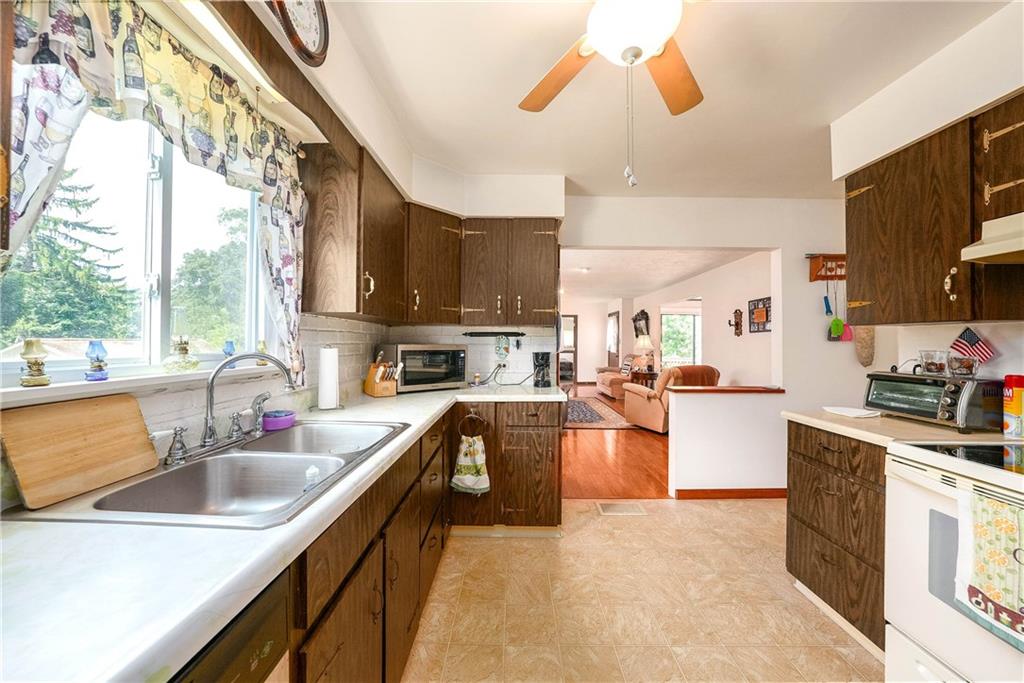 5403 Hardt Road Gibsonia, PA 15044 - Photo 12 of 41 a kitchen with stainless steel appliances a sink dishwasher a stove top oven a dining table and chairs with wooden floor