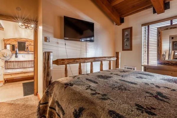 a bedroom with a bed a flat screen tv and dresser