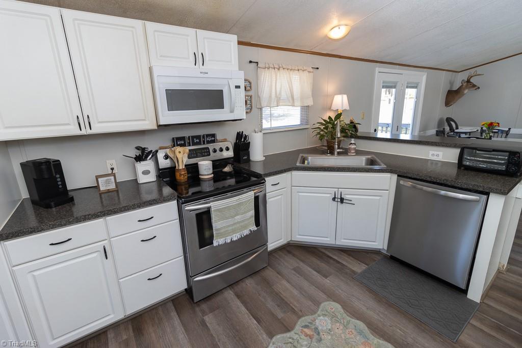8280 Stafford Mill Road Oak Ridge, NC 27310 - Photo 16 of 40 THE KITCHEN WITH VINYL PLANK WOOD LOOK FLOORS, STAINLESS STEEL RANGE AND MICROWAVE.
