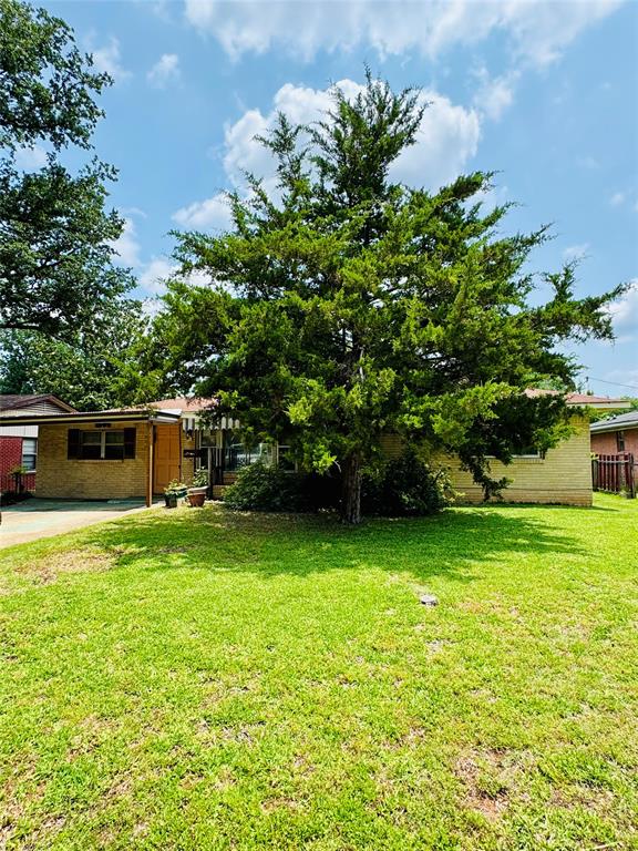 a tall yellow house with a big yard and large trees