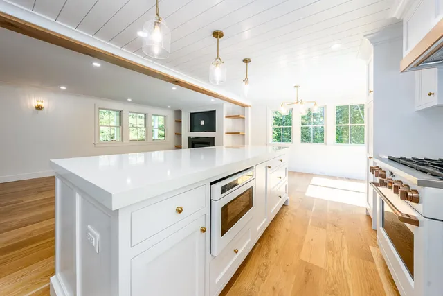 a large white kitchen with stainless steel appliances granite countertop a stove and a sink