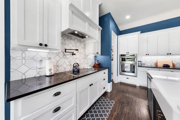 a living room with stainless steel appliances furniture a rug and a kitchen view