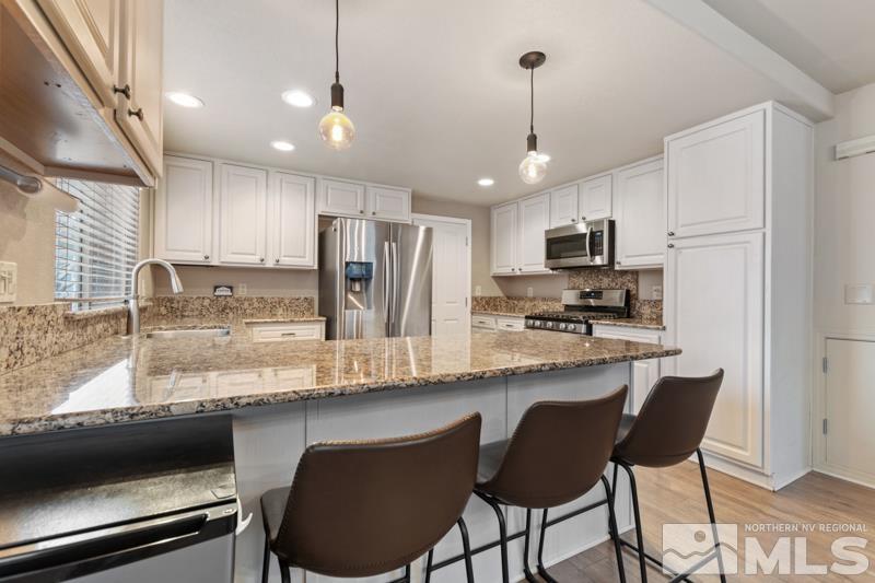 7595 Whimbleton Way Reno, NV 89511 - Photo 10 of 36 a kitchen with kitchen island granite countertop a table chairs microwave and cabinets