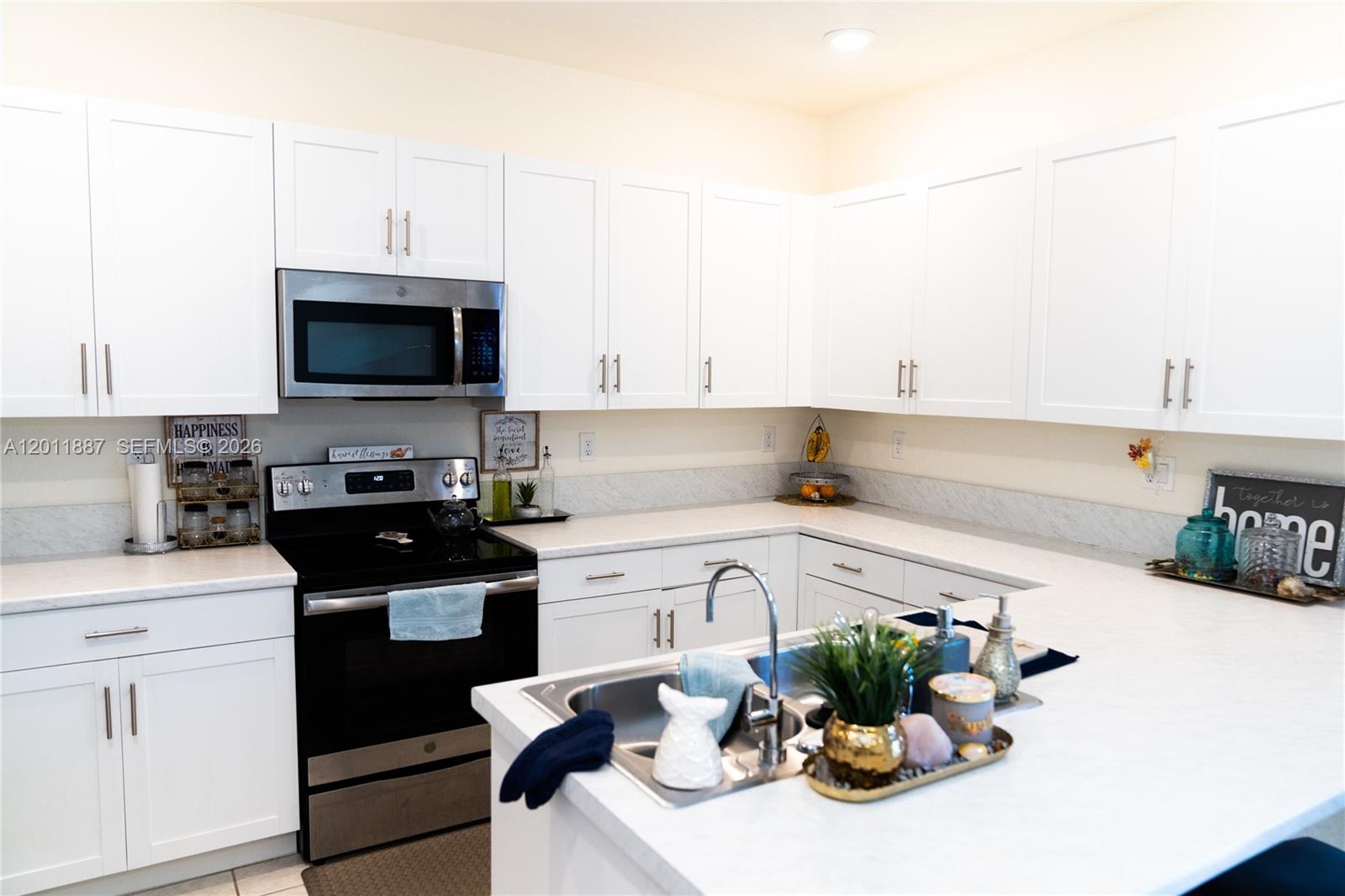 10599 West 33rd Court Hialeah, FL 33018 - Photo 12 of 39 a kitchen with stainless steel appliances white cabinets a sink and a stove