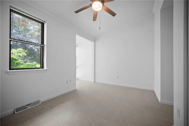 an empty room with chandelier fan and windows