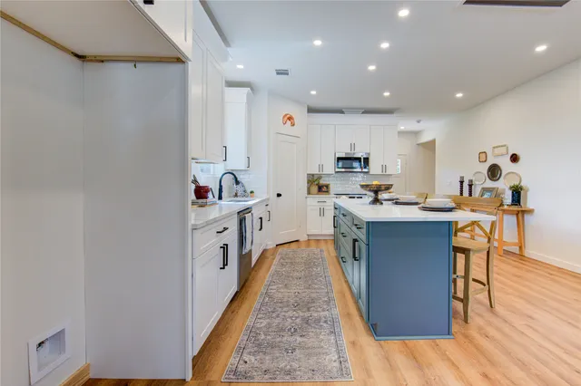 a kitchen with stainless steel appliances kitchen island granite countertop a stove a sink and a refrigerator