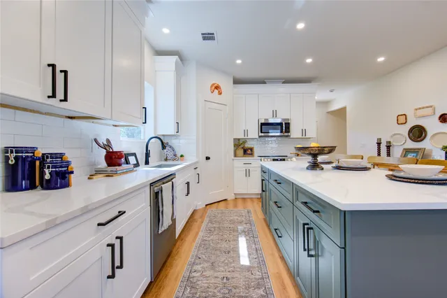 a kitchen with stainless steel appliances granite countertop a sink dishwasher stove and white cabinets