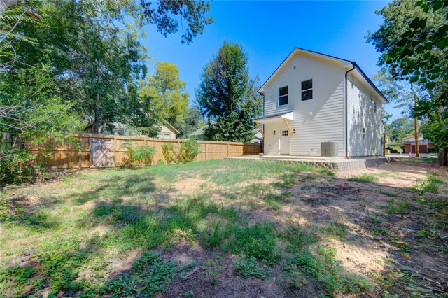 a white house with a small yard and big trees with wooden fence