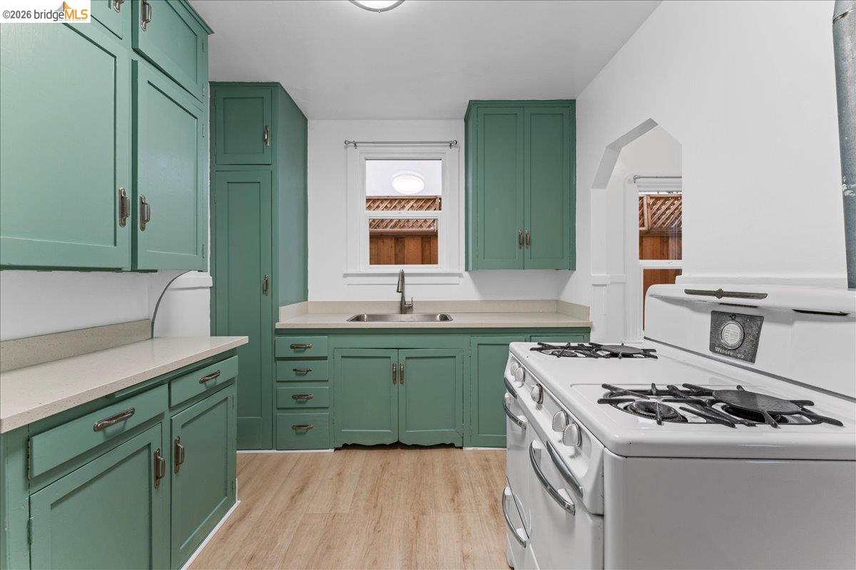 1127 Key Rte Boulevard Albany, CA 94706 - Photo 34 of 36 Kitchen with white range with gas cooktop, green cabinetry, light countertops, and light wood-type flooring