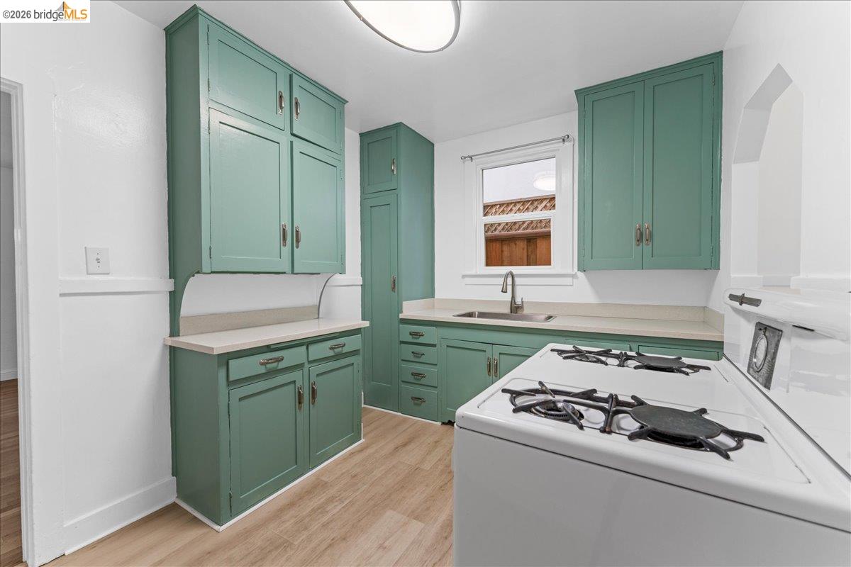 1127 Key Rte Boulevard Albany, CA 94706 - Photo 35 of 36 Kitchen featuring green cabinetry, white range with gas stovetop, light countertops, and light wood finished floors