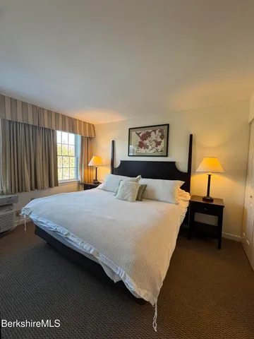 a living room with stainless steel appliances furniture a rug and a kitchen view