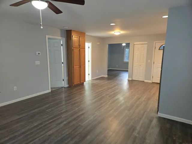 an empty room with wooden floor ceiling fan and window