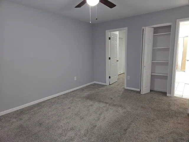 an empty room with a ceiling fan and window