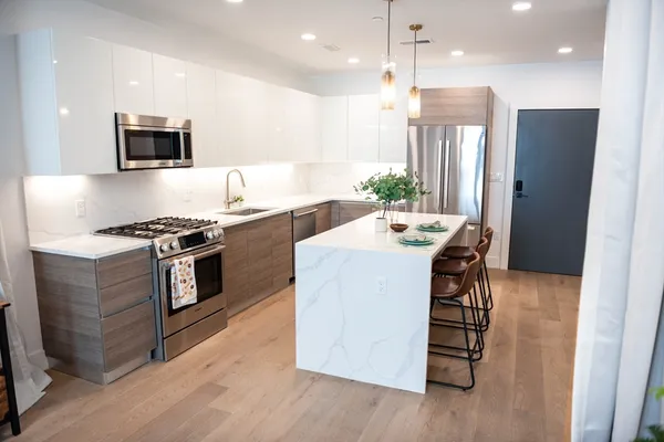 a kitchen with stainless steel appliances kitchen island hardwood floor sink and stove