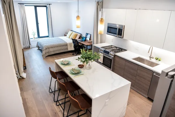 a living room with stainless steel appliances furniture a dining table and a window
