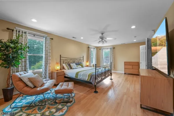 a spacious bathroom with a granite countertop double vanity sink a mirror a window and a bathtub