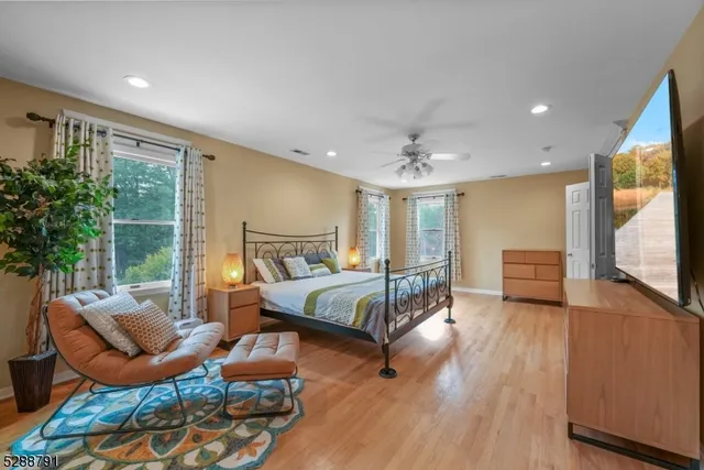 a spacious bathroom with a granite countertop double vanity sink a mirror a window and a bathtub