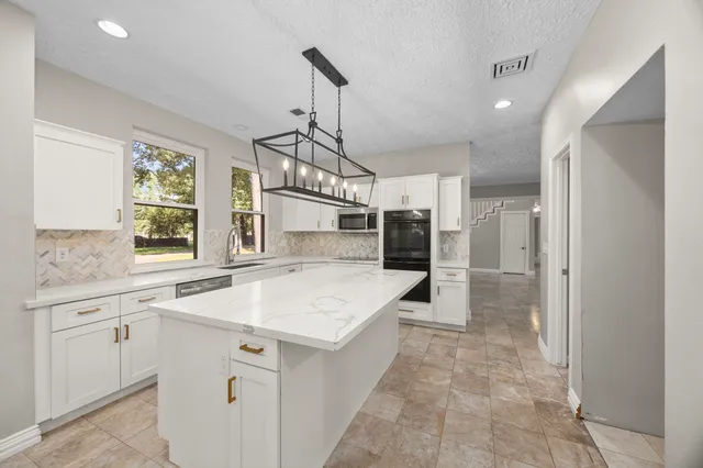a view of a kitchen with stainless steel appliances granite countertop a sink and a stove top oven