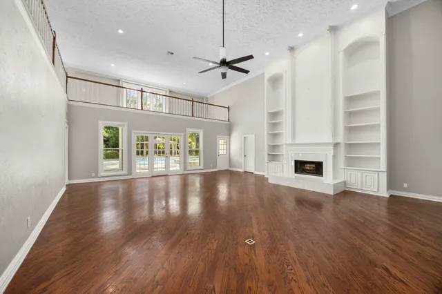 a view of an empty room with window and wooden floor