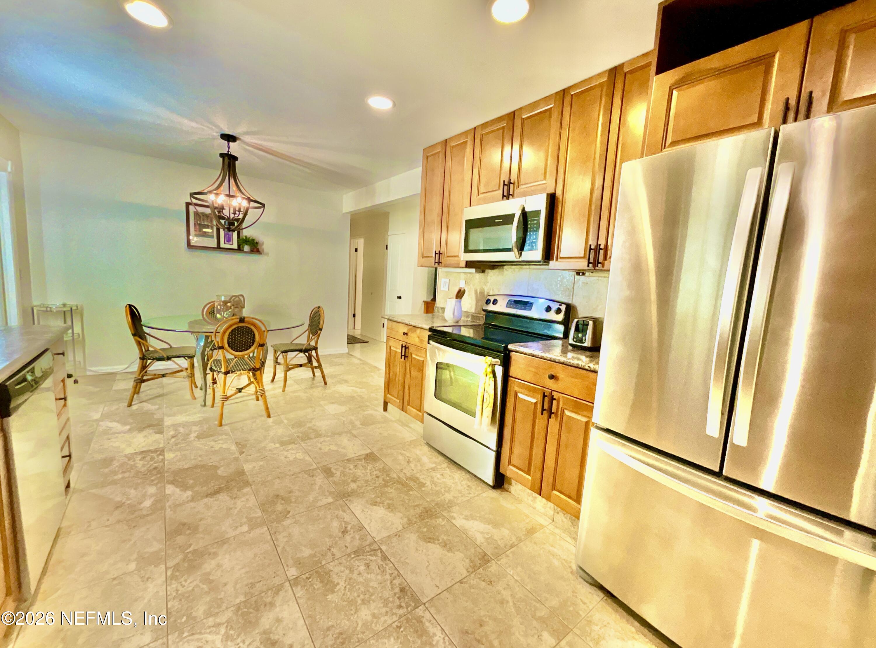 17221 Northeast 77th Lane Hawthorne, FL 32640 - Photo 26 of 59 a kitchen with stainless steel appliances granite countertop a refrigerator a stove a dining table and chairs with wooden floor