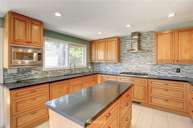 a kitchen with granite countertop stainless steel appliances a sink stove and cabinets