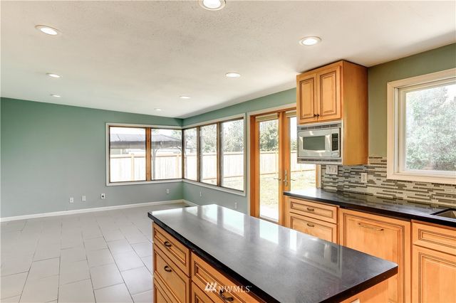 a living room with stainless steel appliances granite countertop a sink a granite counter tops and a large window