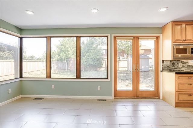 a view of an empty room with a window and a kitchen