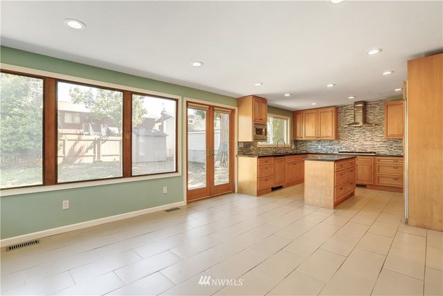a large kitchen with stainless steel appliances granite countertop a stove and a large window