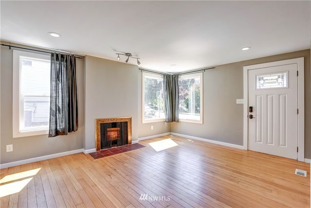 a view of an empty room with a window and fireplace