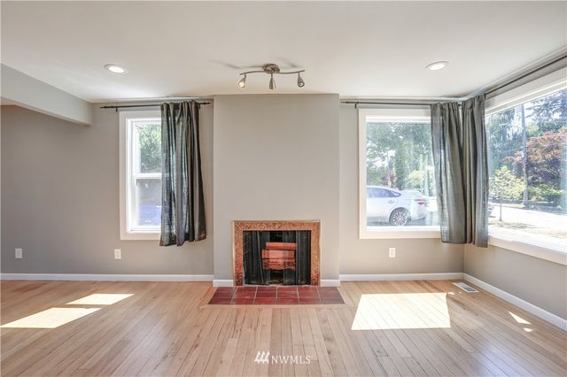 a view of an empty room with a window and wooden floor