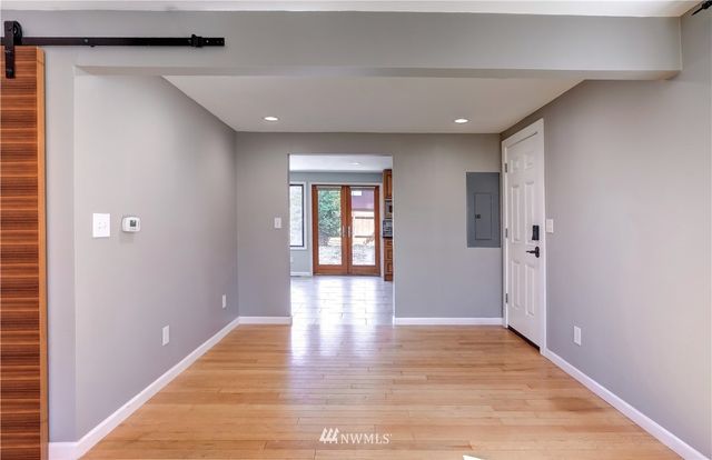 a view of an entryway of a house and empty room with wooden floor