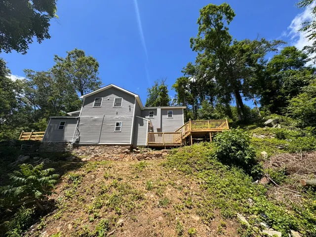 a backyard of a house with wooden fence and large trees