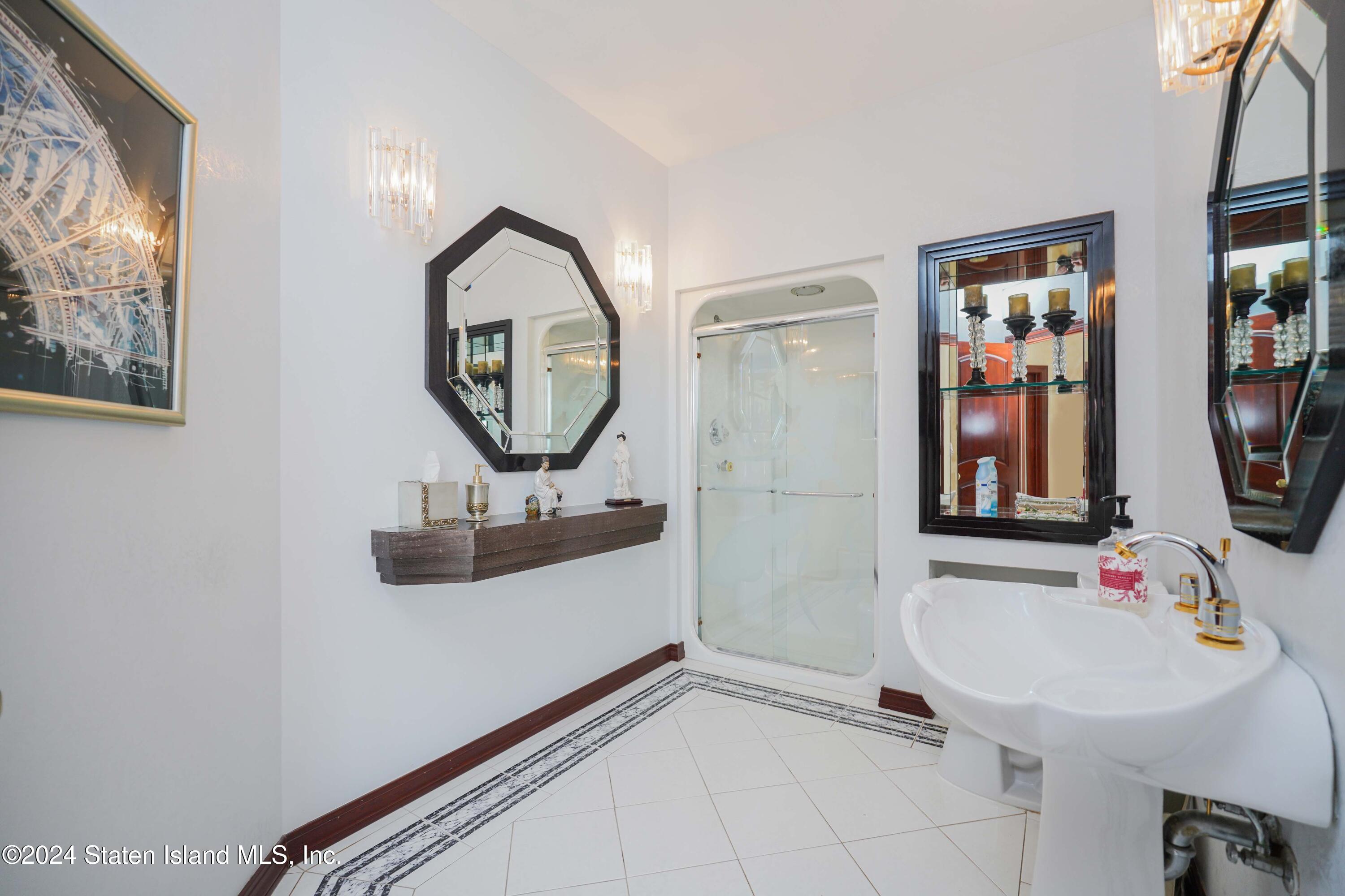 12 Romer Road Staten Island, NY 10304 - Photo 28 of 63 a bathroom with a sink a mirror and a painting on the wall