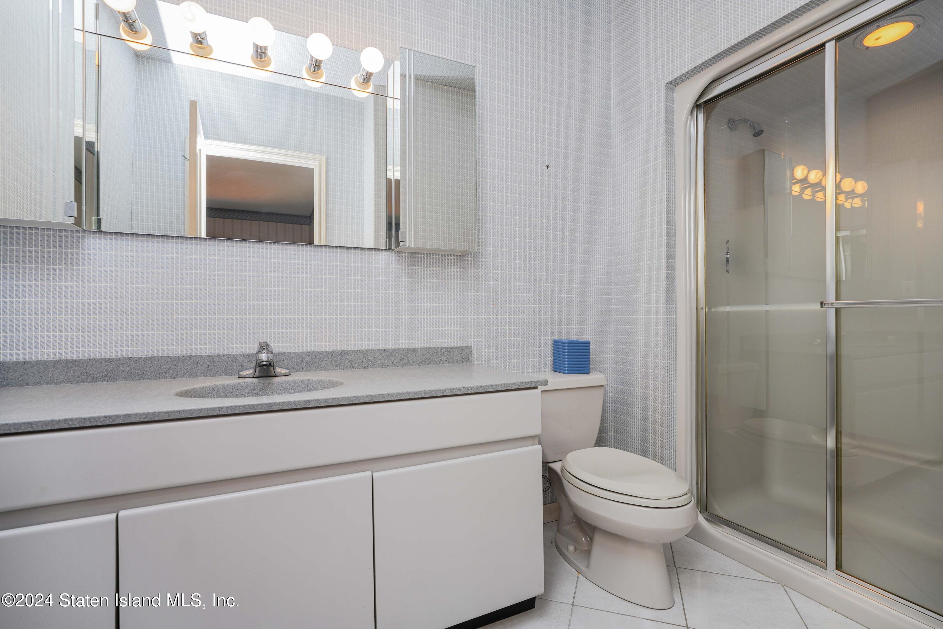 12 Romer Road Staten Island, NY 10304 - Photo 40 of 63 a bathroom with a toilet a sink a glass door and shower
