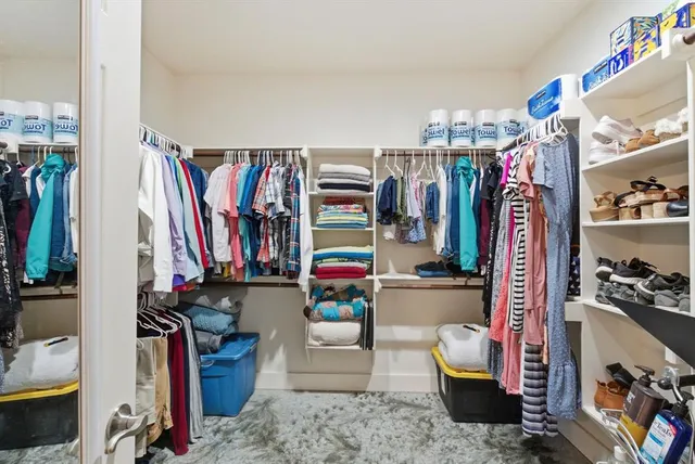 a view of walk in closet with clothes and shoes